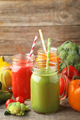 Vegetables smoothie in jars on wooden table
