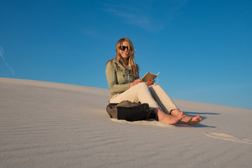 Fototapeta na wymiar Happy young woman, blonde sits in the desert