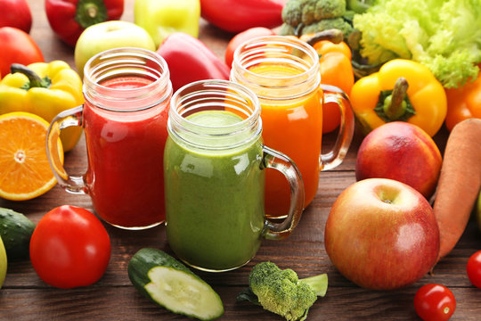 Vegetables smoothie in jars on wooden table