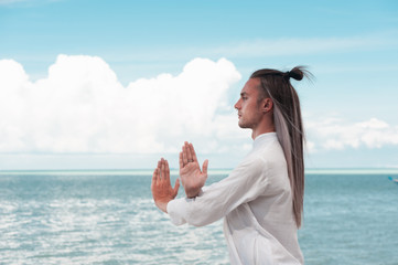 Handsome man is practicing Taijiquan on the beach