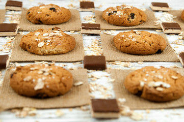 Oatmeal cookies and chocolate pieces on a white vintage table.