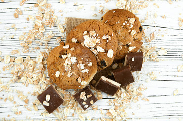 Oatmeal cookies and chocolate pieces on a white vintage table.
