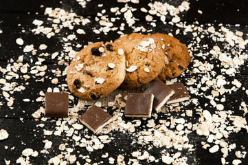 Homemade cookies and chocolate on a black table.