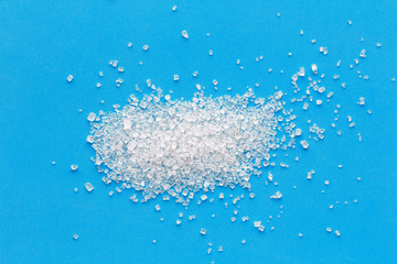 Fototapeta na wymiar spoon of sugar scattered on a bright blue background