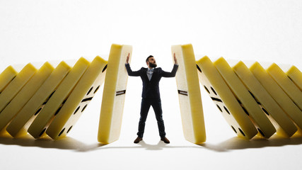 The man stops the falling dominoes. Concept of crisis management.