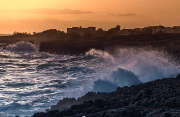 amazing sunset over sea and cliff. Taranto seafront landscape. Water spray on the rocks. stunning panorama