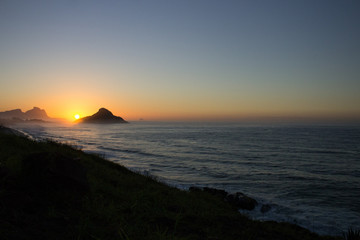 Obraz premium color photography of sunrise between mountain on macumba beach in rio de janeiro city