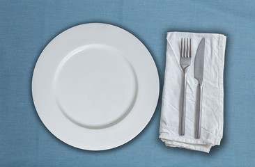 Leerer Teller und Besteck auf blauem Stoff