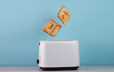 Roasted toast bread popping up of stainless steel toaster on a b