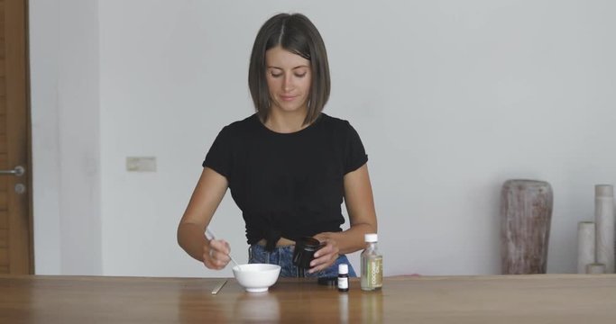 Young pretty woman makes toothbrush independently from ecological natural materials at home. Girl pouring baking soda in the jar. Zero waste concept 4k