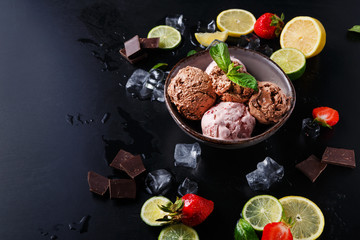 Portion of ice cream scoops with fruit on black