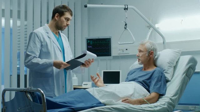 In the Hospital, Recovering Senior Patient Lying in Bed Talks with a Friendly Doctor. Modern Hospital Ward where People Get Best Health Care. Shot on RED EPIC-W 8K Helium Cinema Camera.