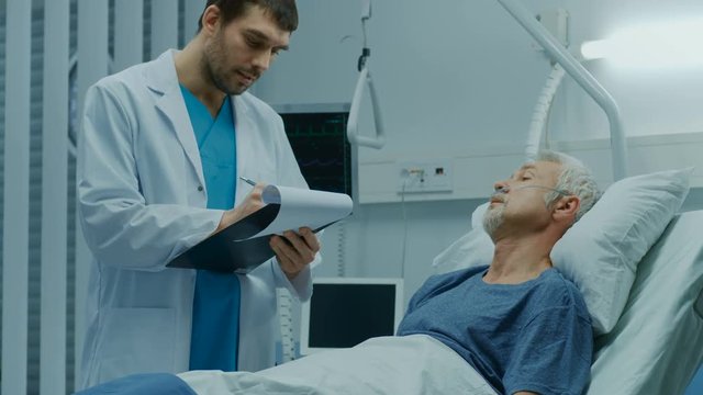 In the Hospital, Recovering Senior Patient Lying in Bed Talks with a Friendly Doctor. Professional Doctor Asks Patient Vital Questions in the Modern Geriatrics Ward. 