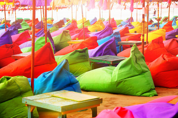 Multicolored bright beach umbrellas, ottomans and tables in the beach cafe. Summer multicolored background. Bali, Indonesia.