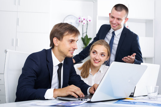 Three satisfied coworkers working in company office