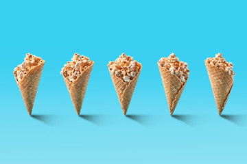 Popcorn in ice cream cones on blue background.