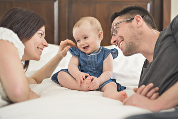 happy family mother, father and baby at home in bed