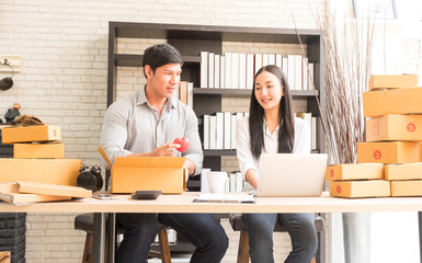 professional young online shopping company team of two co worker with box of products in office background and face to camera. selective focus photo.