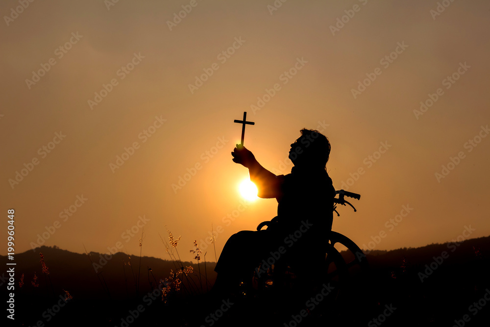 Wall mural Silhouette disabled with wheelchair using cross to praise God,Trust concept,concept pray.