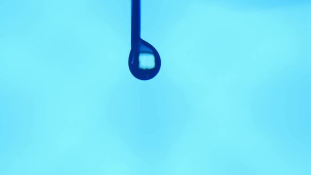 An abstract macro of a brilliant blob of water having a lit window inside. A water brooklet trinkles down in a turquoise aboratory.