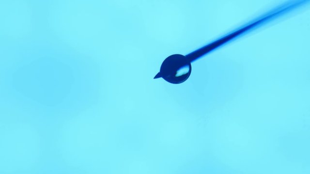   An artistic macro of a transparent blob of water having a lit hole inside. A water brooklet dribs down in a turquoise aboratory.