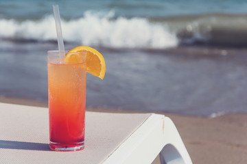 Glasses with colored cocktails on the beach with blue water in the background