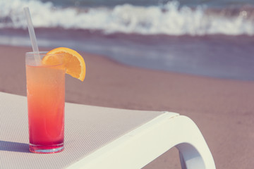 Glasses with colored cocktails on the beach with blue water in the background