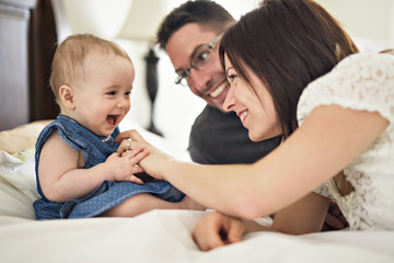 happy family mother, father and baby at home in bed
