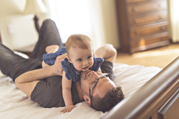 Obraz premium Father playing with her baby in the bedroom