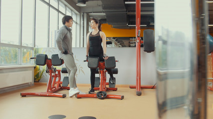 Young woman talking with coacher in workout room