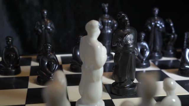 Chess pieces in the form of Slavic Cossacks stand on a chessboard on a dark background. Close-up, high detail. Rotation. 4K, 25 fps