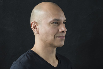 Obraz premium Profile portrait of a man with a shaved head, looking away from the camera