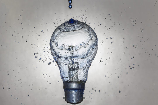 Blue water drops on light bulb splashing in all directions