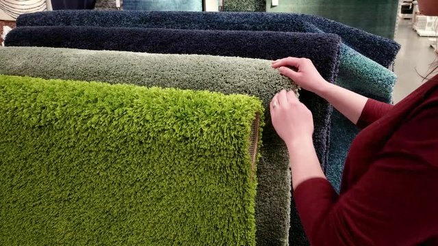Woman choosing carpet in the store, closeup