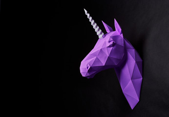 Horizontal sideview of violet deep shadowed unicorn's head hanging on black smooth wall. Horse has intresting geometrical shape and straight lines. Original decoration for modern design.