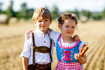 Two kids, boy and girl in traditional Bavarian costumes in wheat field