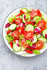 Fresh vegetable salad with tomatoes, cucumbers, sweet pepper and sesame seeds. Vegetable salad on white plate