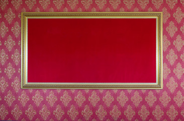 Elegant golden blank picture frame on red textured wall background