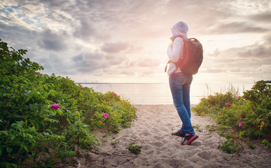sea in sunset light. Woman in Lahemaa natural park coastal landscape with beautiful sky. Person with rucksack