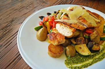 Grilled chicken breast, zucchini and garden vegetable power bowl. White plate on old vintage wooden table. Healthy diet food concept, Close up view