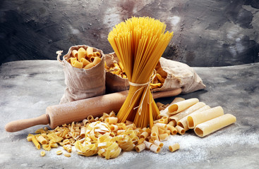 Various mix of pasta on grey rustic background. Diet and food concept.