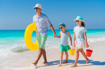 Family of dad and kids walking on white tropical beach on caribbean island with beach toys. Family beach holidays