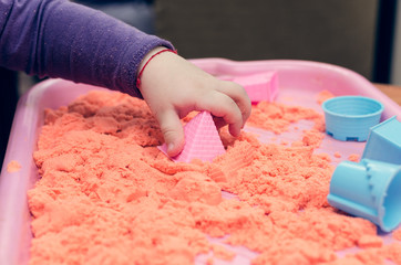 The hands of a child playing with kinetic sand