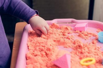 Obraz na płótnie Canvas The hands of a child playing with kinetic sand