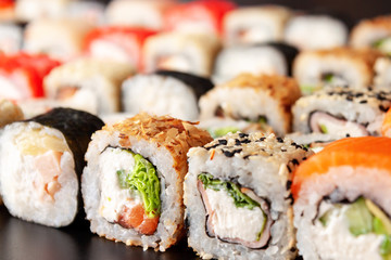 Assorted sushi rolls on black background