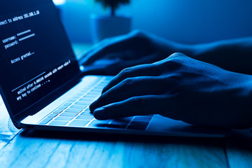 A computer programmer or hacker prints a code on a laptop keyboard to break into a secret...
