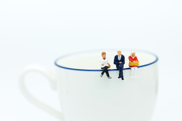 Miniature people : Business team sitting on cup of coffee and having a coffee break. Image use for business concept.
