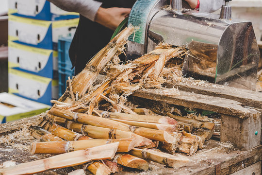 Man queezing sugar cane juice at street food market