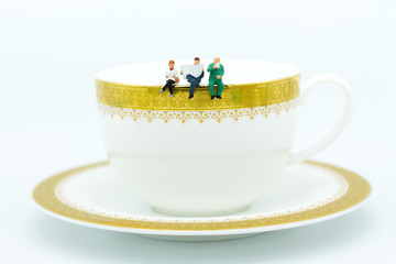 Miniature people : Business team sitting on cup of coffee and having a coffee break. Image use for business concept.