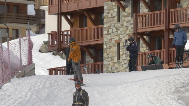 People snowboarding and skiing in front of a building 
